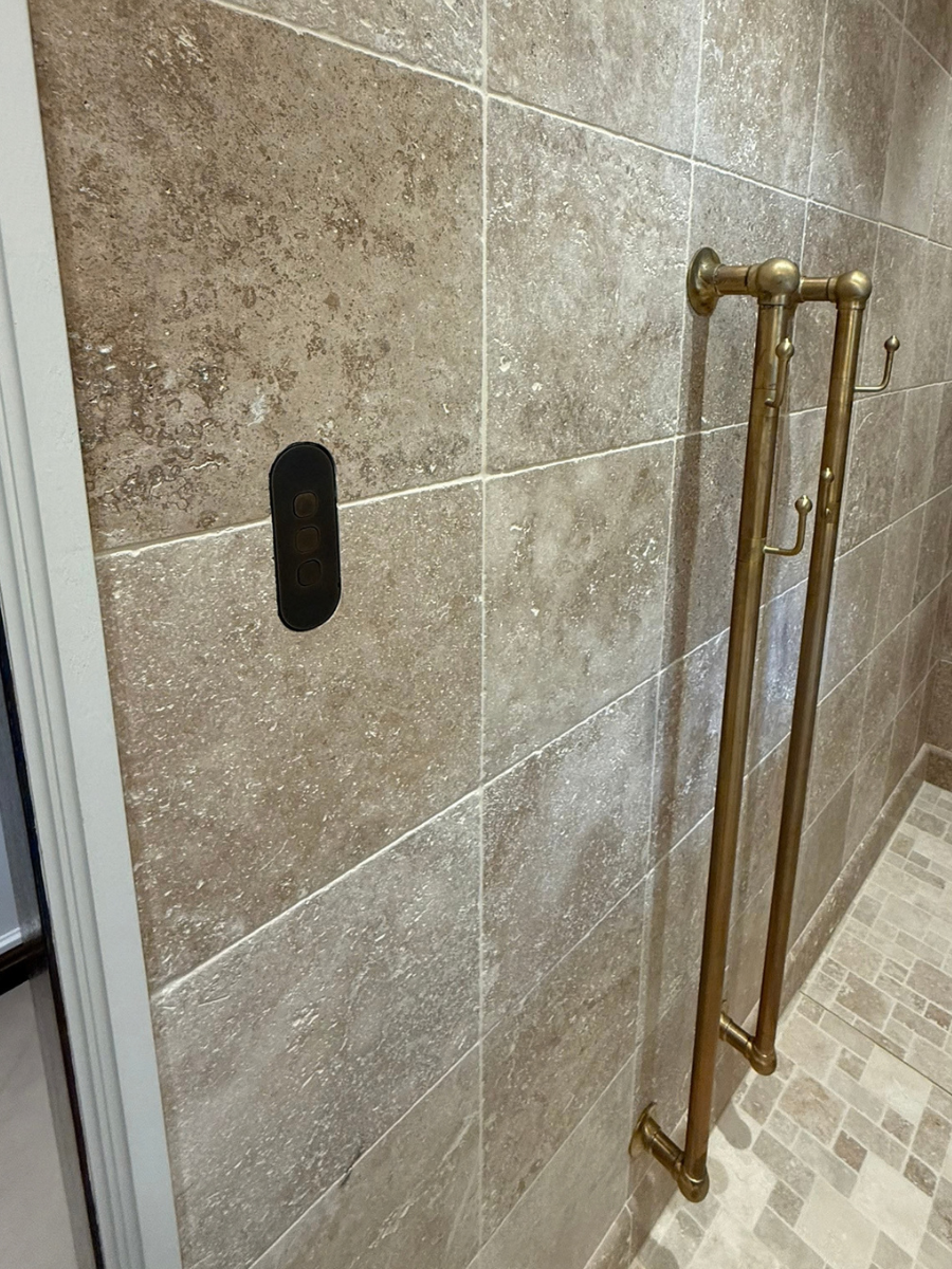Flush-mounted ZETR plate with brass fittings in a tiled bathroom